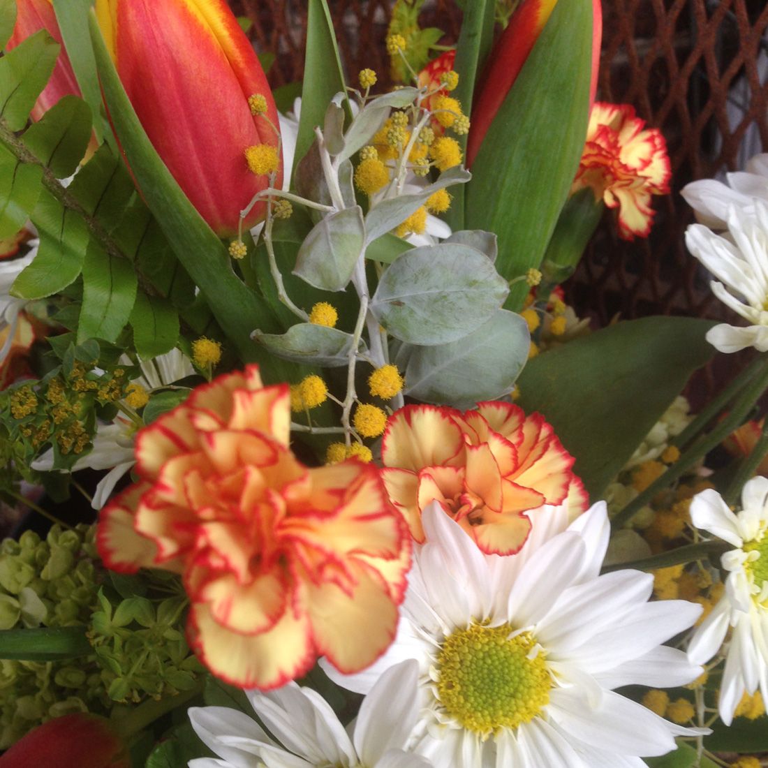 medium-sized bouquet of flowers and greens, wrapped in kraft paper